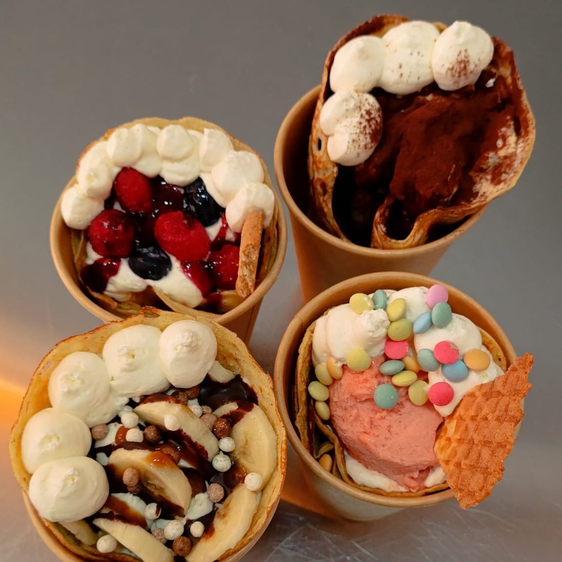 Quatro crepes em copo, cada uma com a sua cobertura, de tiramisù a banana e chocolate