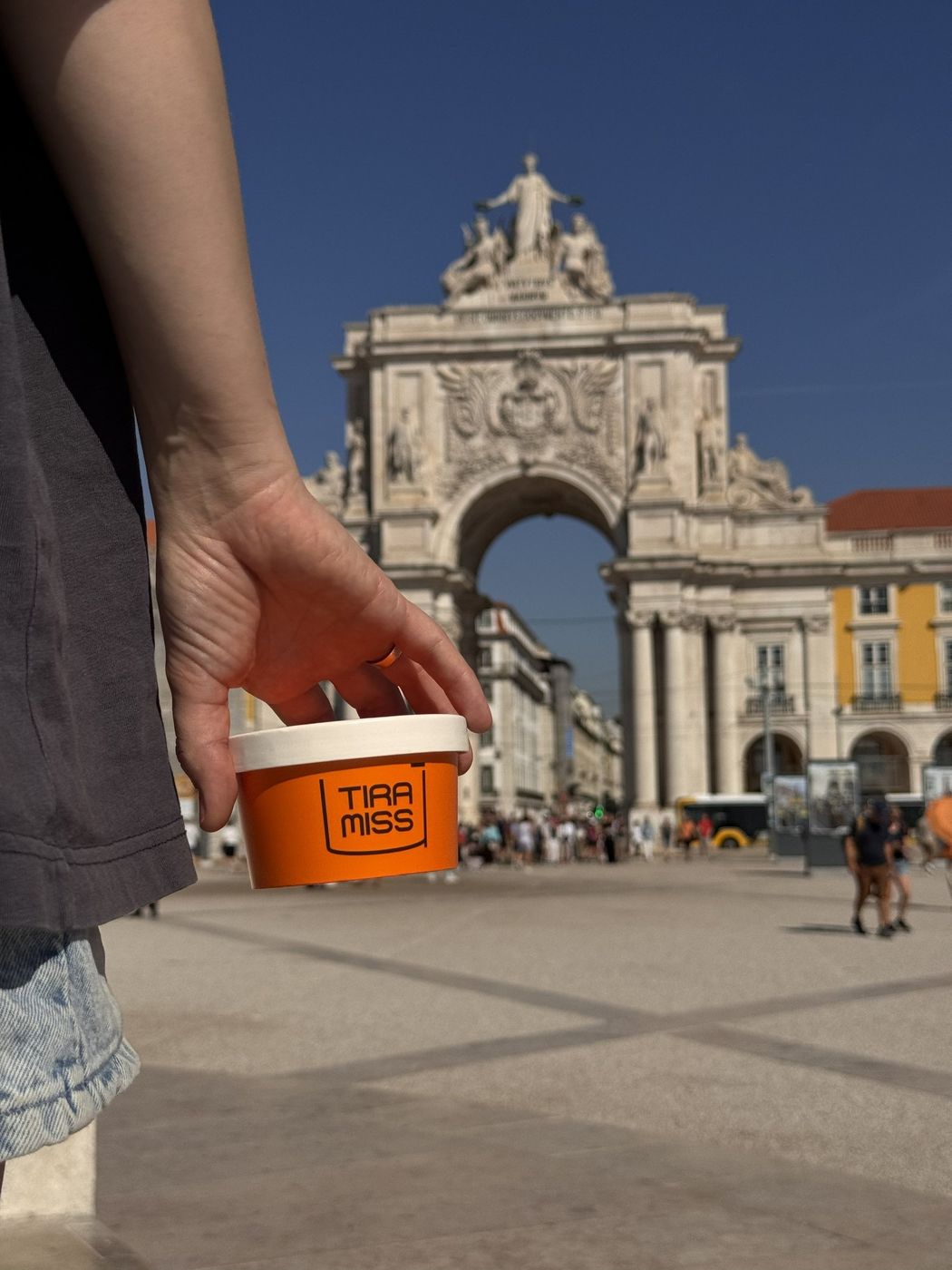Copa TiraMissÙ na mão, com o Arco da Rua Augusta ao fundo